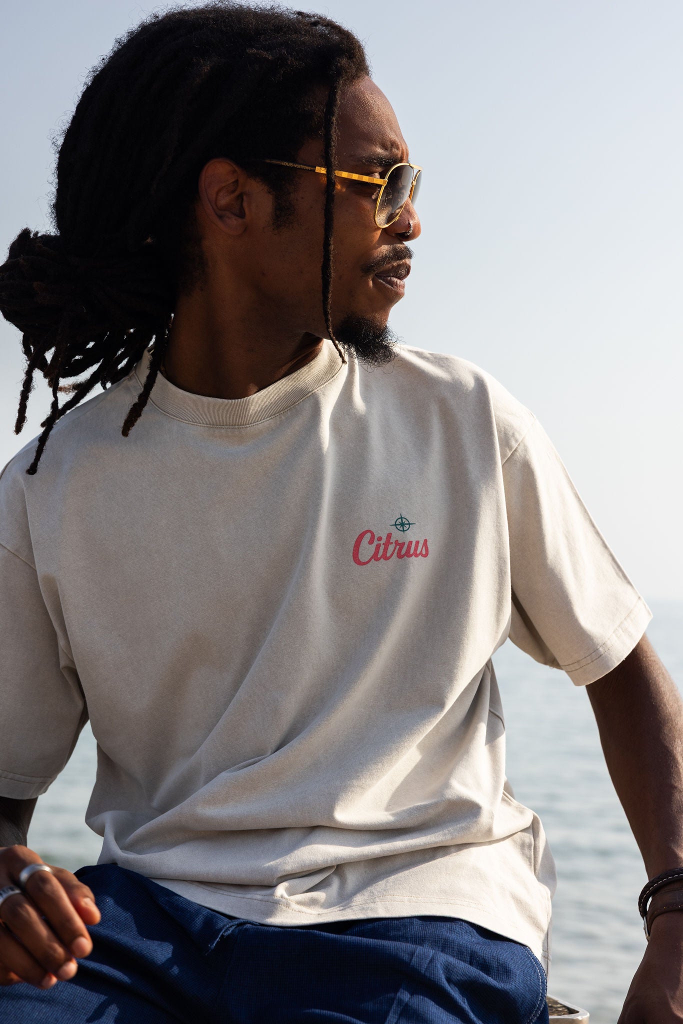 Man wearing a white t-shirt with 'Citrus' logo sitting by the water. high quality knit 100% cotton.