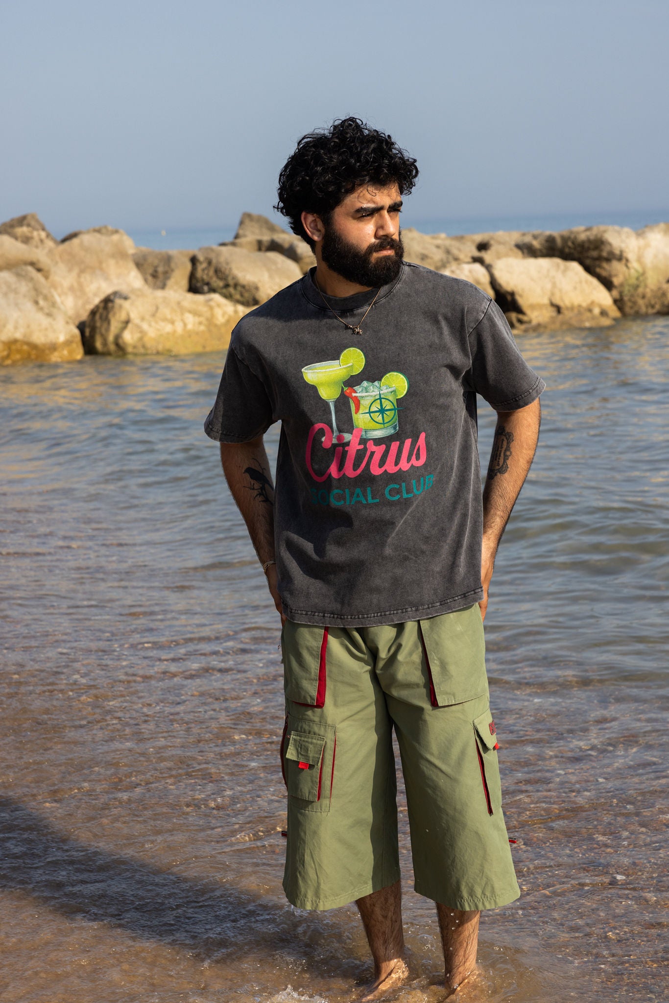 Man standing by the water wearing a t-shirt with graphics of two margaritas. with the words Citrus Social club.